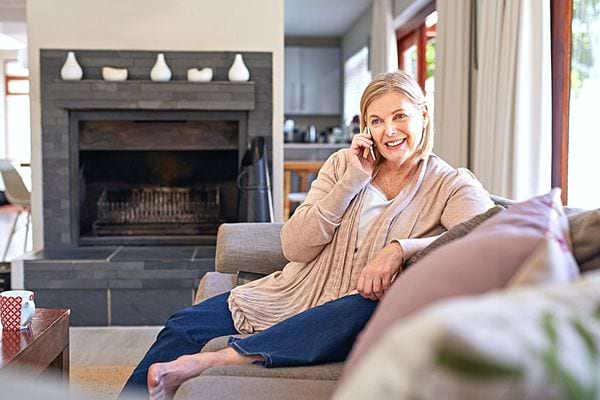 Une femme blonde qui est au téléphone sur son canapé 