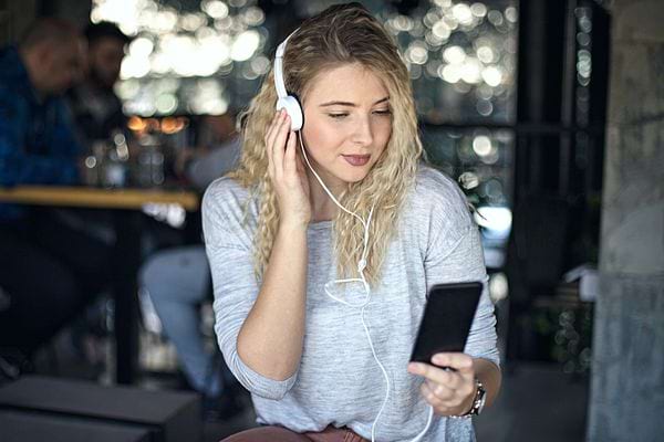 Une femme blonde qui écoute de la musique avec un casque blanc 