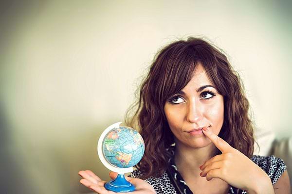 Une femme pensive tenant un petit globe dans sa main droite 