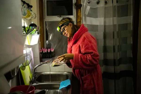 Une femme devant un évier dans la cuisine avec une lampe sur la tête