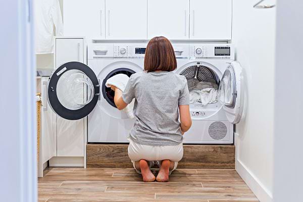 Une femme devant un lave-linge et un sèche-linge 
