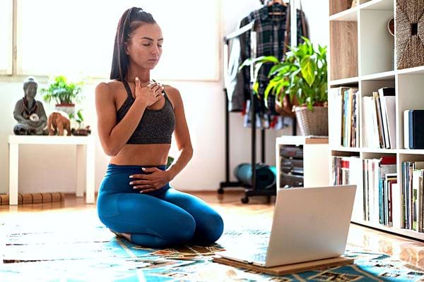 Une femme qui fait du yoga devant son ordinateur 