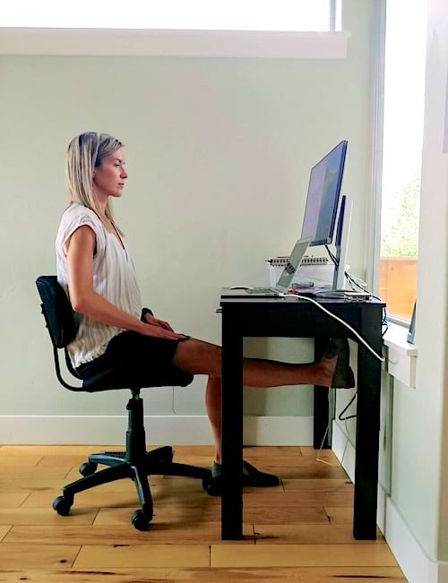 Une femme qui &eacute;tire sa jambe sous son bureau 