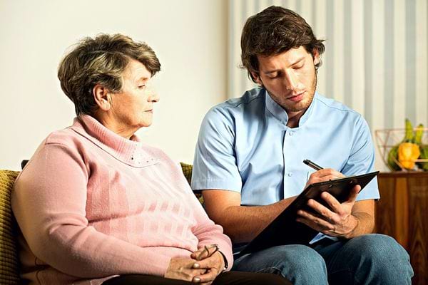 Un homme qui écrit à côté d'une dame âgée 