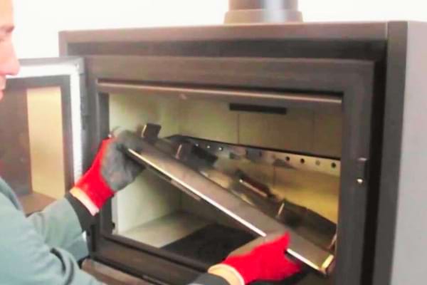 Un homme qui change un bruleur de poêle à bois pour des pellets de lin