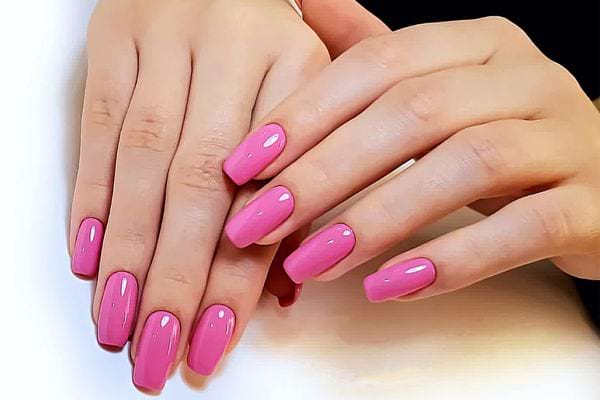 Des mains avec du vernis rose 