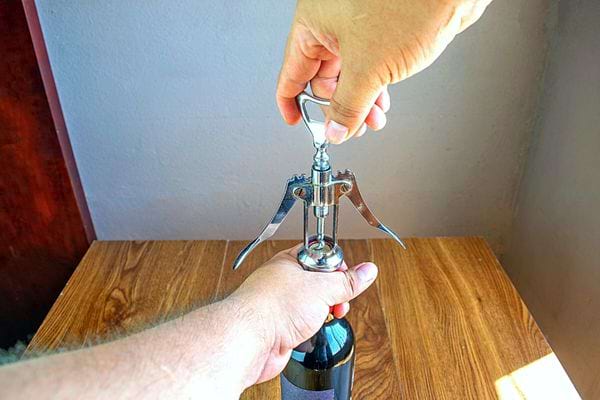 Une personne qui débouche une bouteille de vin