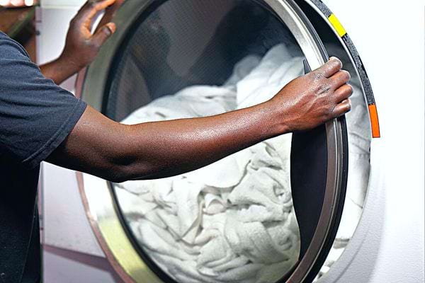 Une personne noir devant un lave-linge 