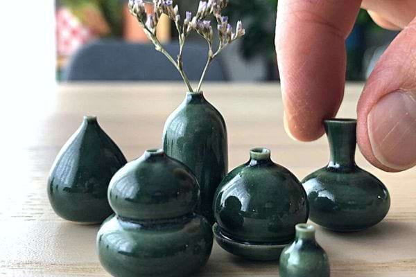 Une personne qui touche pleins de petits objets en poterie vert