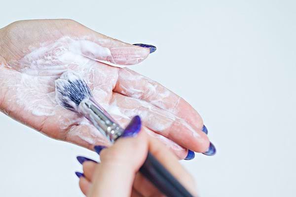 Une femme ayant un pinceau dans sa main avec un liquide blanc 