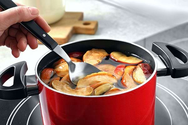 Des pommes dans une casserole d'eau rouge 