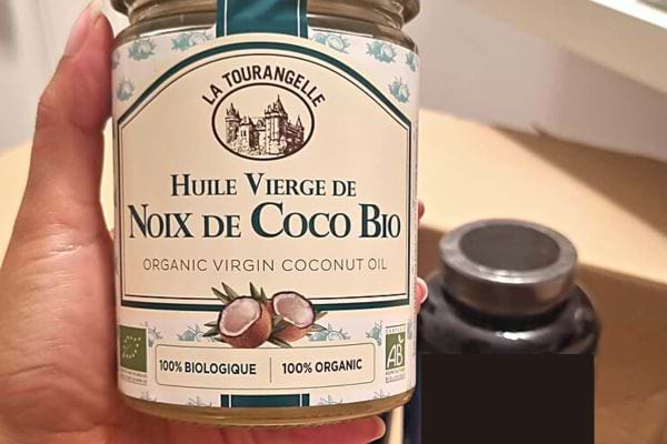 Une personne tenant un pot d'huile de coco 