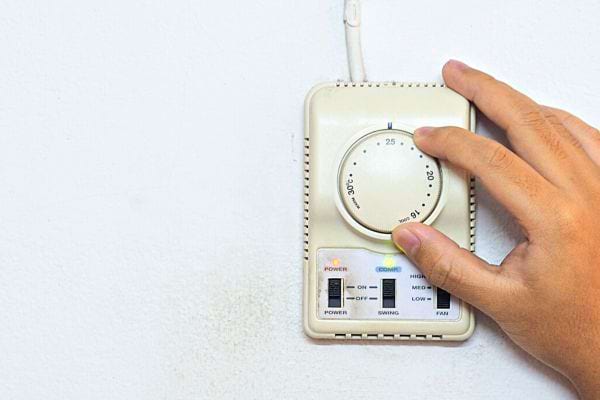 Une personne qui règle le thermostat de son chauffage
