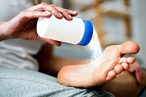 Une personne mettant du talc sur un de ses pieds
