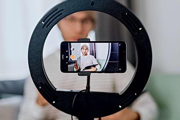 Un homme qui se filme avec son téléphone dans un trépied 