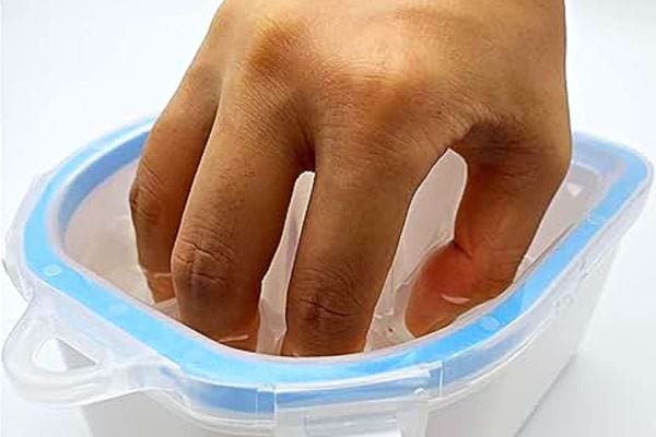 Une personne qui trempe ses ongles dans l'acétone