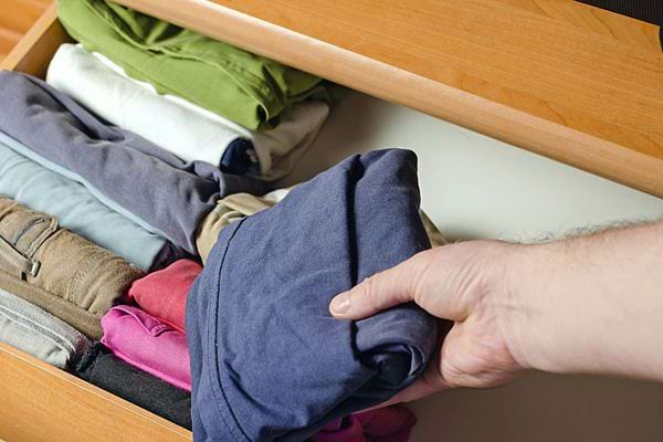 Une personne qui range des vêtements dans un tiroir avec la méthode de Marie Kondo