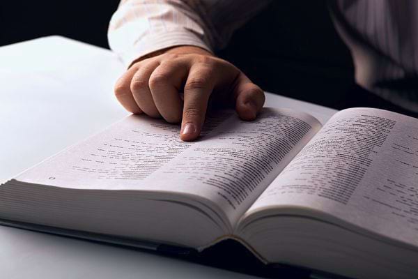 Une main pointant un numéro de téléphone dans un annuaire.