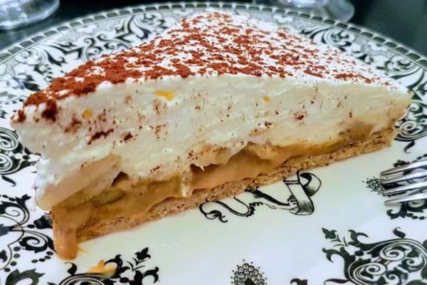 Part de banoffee sans cuisson, avec sa garniture crémeuse et saupoudrée de cacao.