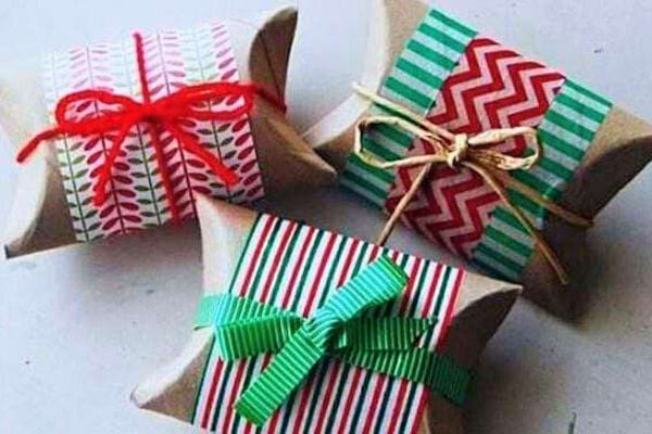 Boîtes cadeaux ornées de rubans rouges, verts et dorés, réutilisant des rouleaux de sopalin pour un emballage festif.