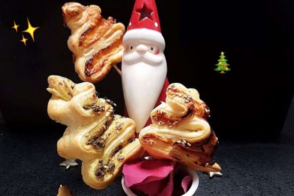 Pains feuilletés en forme d'étoiles empilés autour d'une figurine de Père Noël.