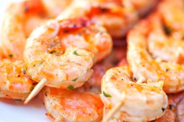 Brochettes de crevettes grillées avec assaisonnement vert.