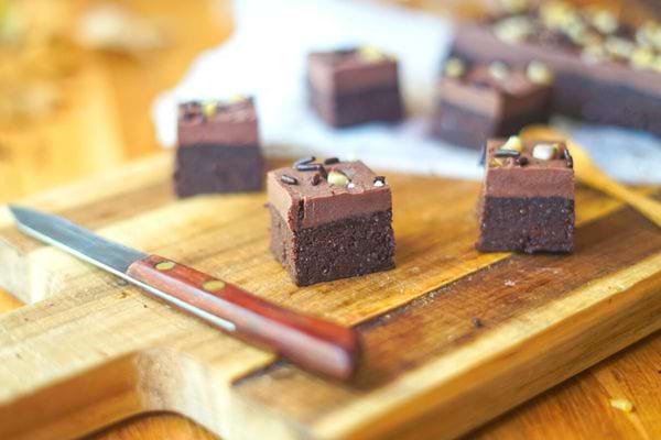 Des carrés de brownie au chocolat, découpés et prêts à servir sur une planche en bois.