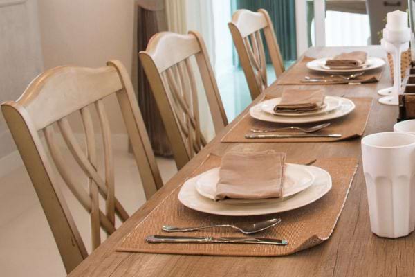 Table simple avec sets de table beige et vaisselle blanche.