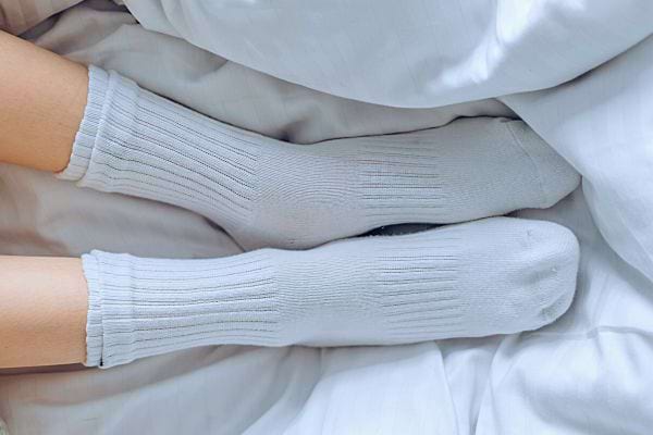 Pieds en chaussettes blanches sur un lit, concept de vêtements portés.