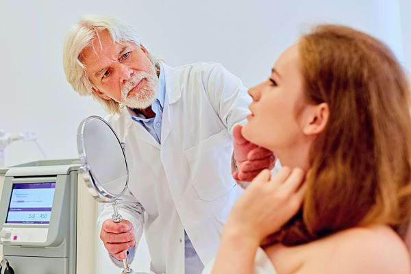 Médecin examinant les rides du cou d'une patiente à l'aide d'un miroir.