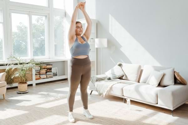 femme qui s'étire avec les bras au dessus de la tête