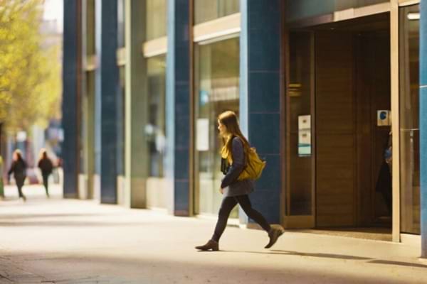 Une étudiante qui sort de la banque après avoir mis en place des virements permanents pour mettre de l'argent de côté