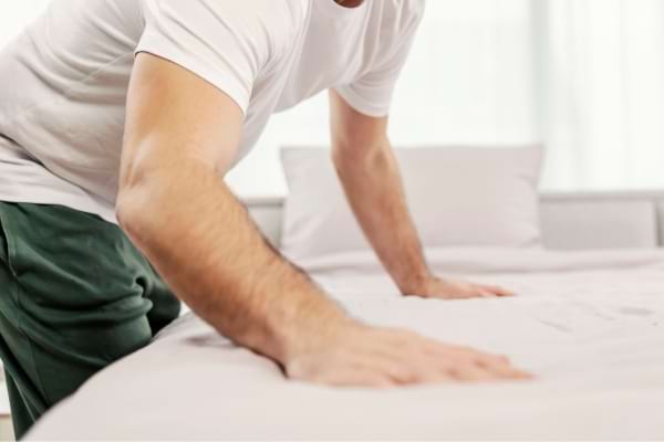 Un monsieur qui fait son lit le matin en se réveillant