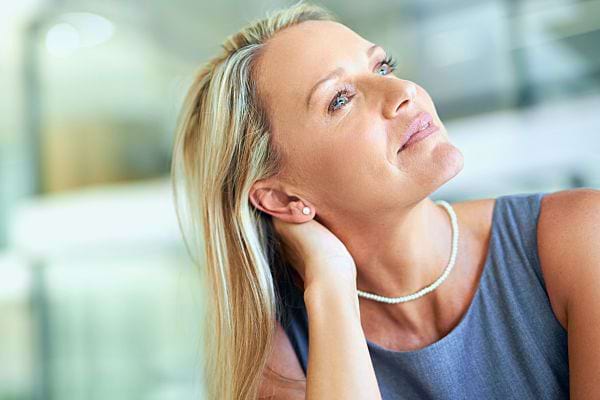 Femme regardant vers le haut, son cou montrant des lignes fines et des rides.