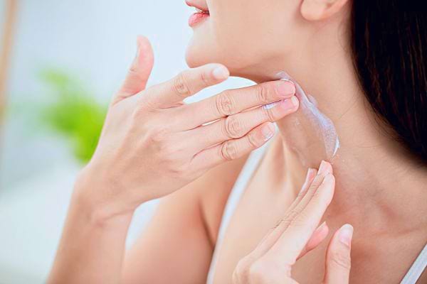 Femme appliquant un gel transparent sur son cou pour traiter les rides du décolleté.