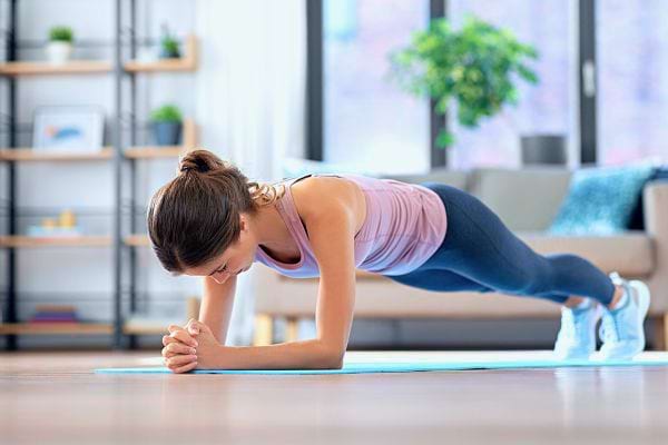 Femme en position de la planche sur les avant-bras pour un gainage intégral.