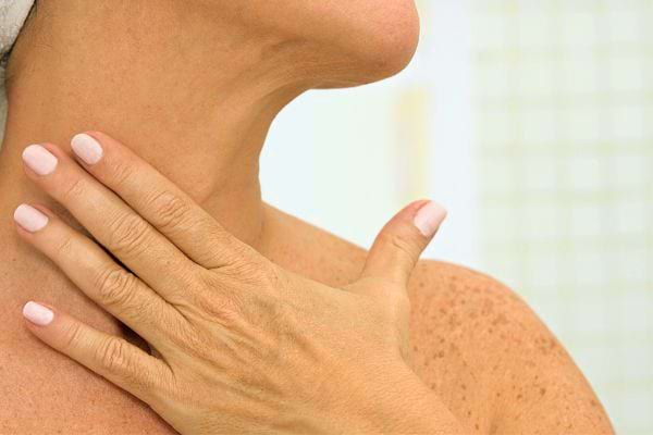 Gros plan sur un cou de femme avec des rides visibles sur le côté.