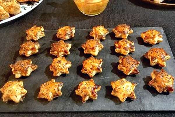 Des feuilletés de petites étoiles au fromage sur un plateau noir pour un apéro chic de Noël