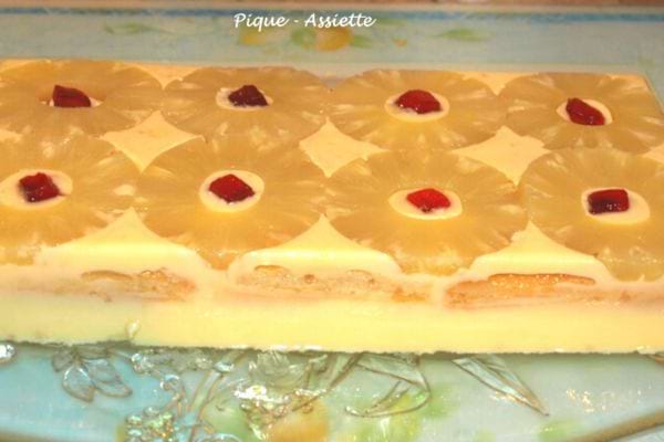 Gâteau frais à l'ananas, décoré de tranches d'ananas et de cerises confites.