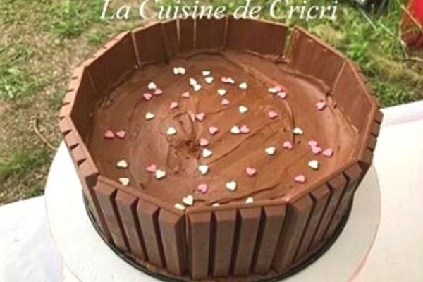 Gâteau Kit Kat sans cuisson, entouré de barres chocolatées et décoré de cœurs en sucre.