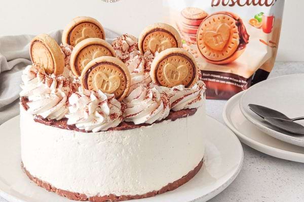 Gâteau sans cuisson style Nutella, décoré de biscuits dorés et crème fouettée sur une assiette blanche.