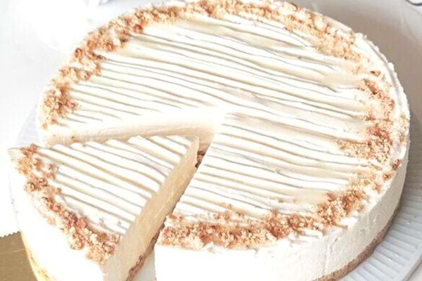 Gâteau au yaourt sans cuisson, avec un glaçage au yaourt et des miettes de biscuits.