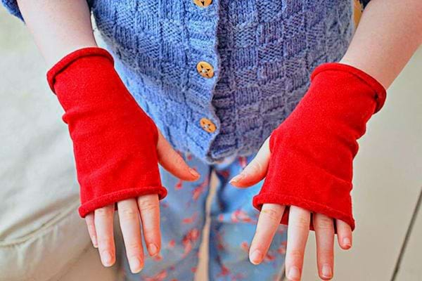 Mitaines conçues en réutilisant des leggings rouges, portées aux mains.