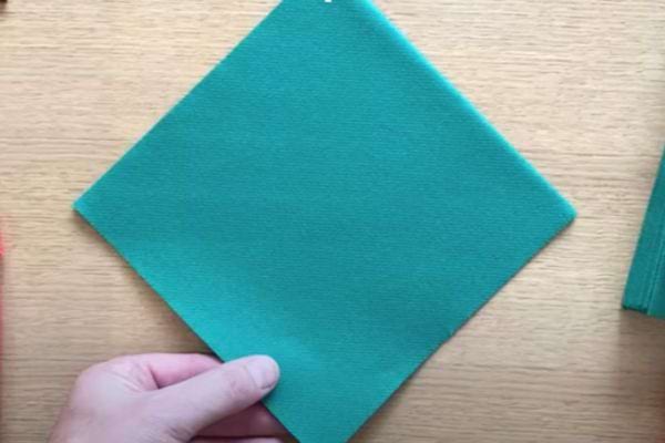 Une serviette verte sur une surface en bois, prête à être pliée.