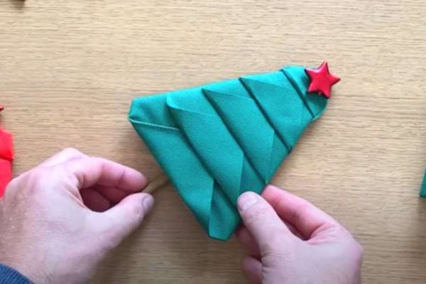 La serviette est pliée en diagonale pour commencer la forme d'un sapin de Noël.