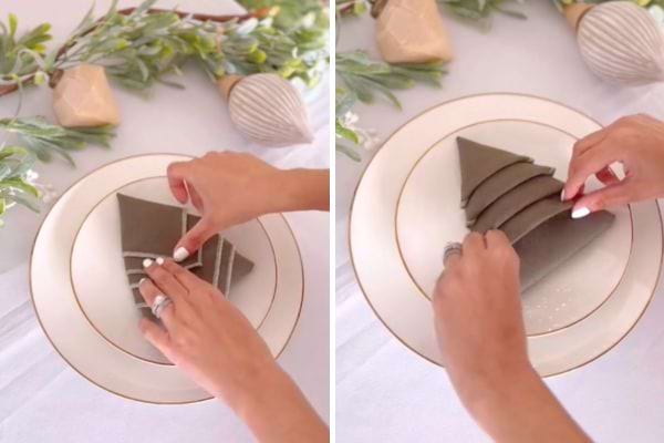 Une serviette grise est pliée en triangle sur une assiette dorée.