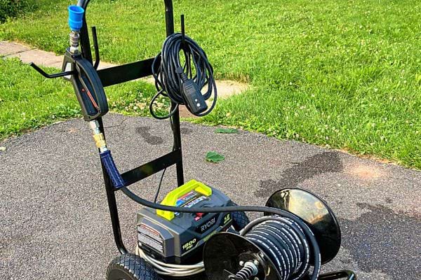 Un nettoyeur haute pression sur une pelouse, probablement utilisé pour nettoyer des surfaces moussues.