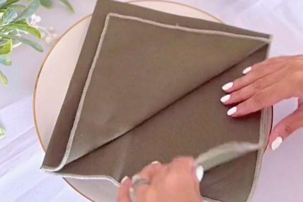 La serviette grise est presque entièrement pliée en forme de sapin.