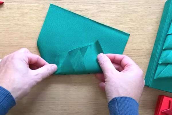 La serviette verte est rabattue pour finaliser la forme de sapin.