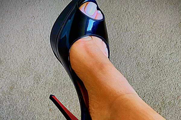 Un pied de femme avec du vernis portant des Louboutin